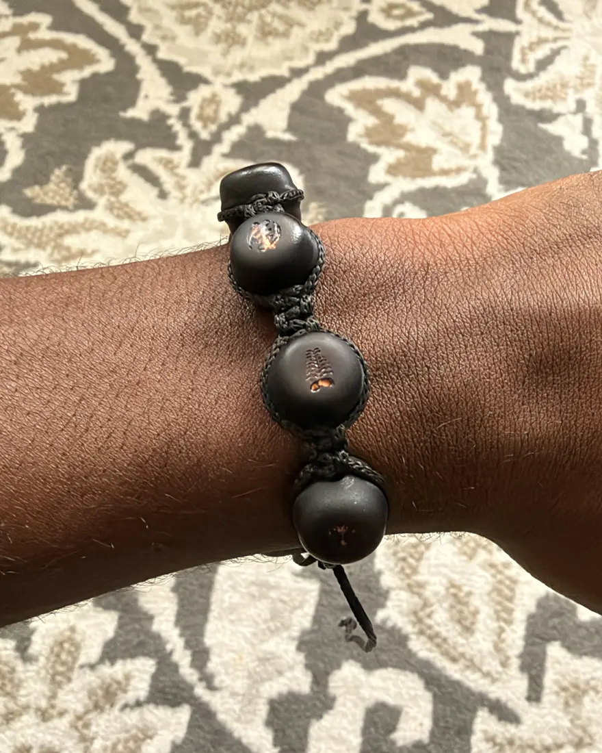 The first M'AKOMA prototype worn on the wrist: three beads with laser-marked Adinkra symbols