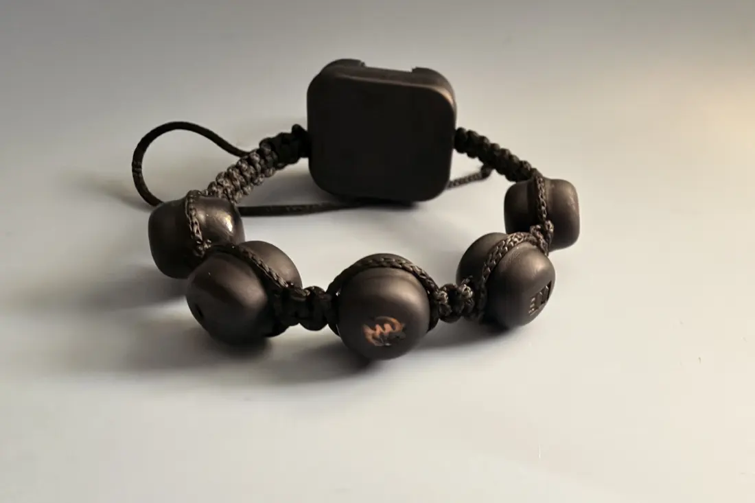 The assembled prototype bracelet: matte black beads and core hub on a knotted cord
